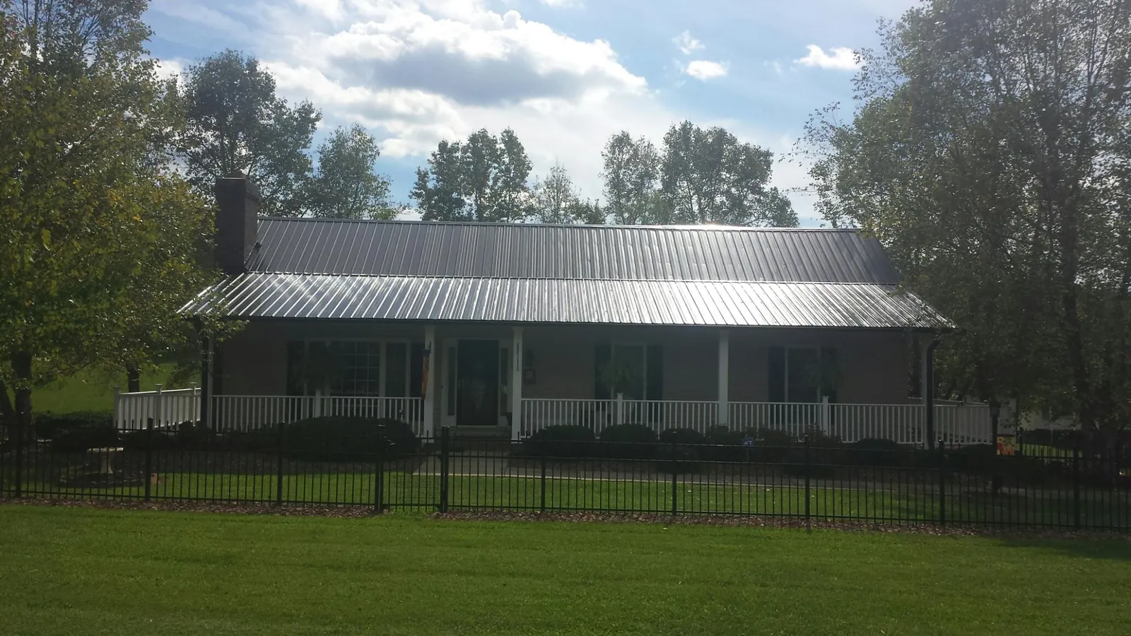 Gray metal roof on a brick ranch with a full width front porch — Gutter Guard Installation work by our crew in Rutland